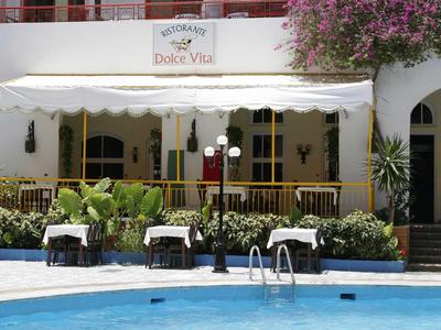 Slunečná terasa s stolky a židlemi vedle hotelového bazénu