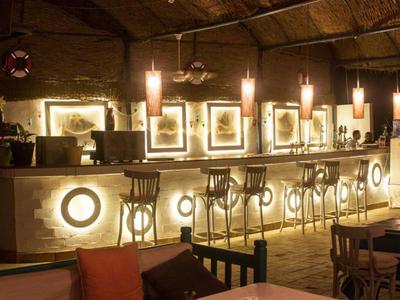 Bar accogliente con bancone illuminato e sgabelli alti in luce calda.