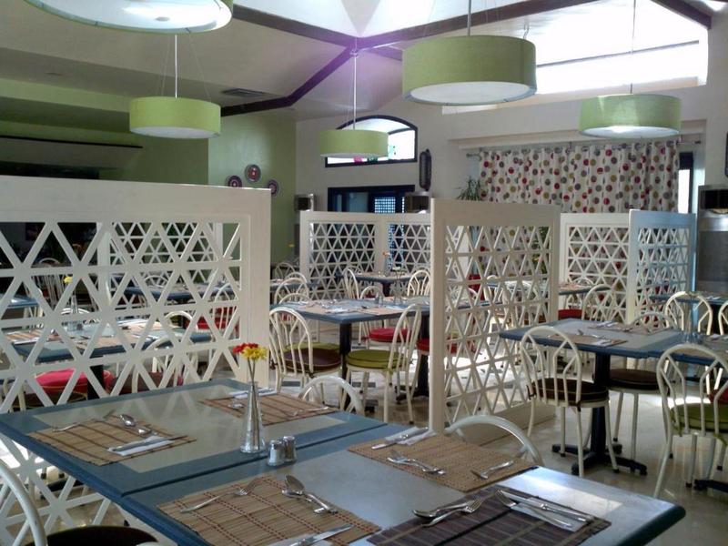 Innenraum eines Restaurants mit hellen Wänden, weißen Trennwänden und gedeckten Tischen.