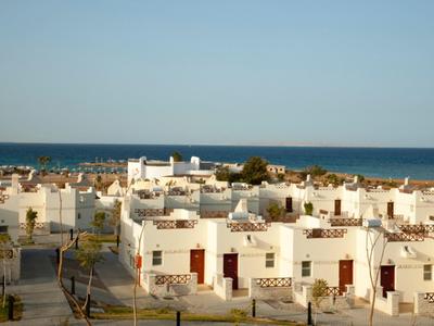 Edifici bianchi vicino alla costa sotto un cielo sereno con vista mare sullo sfondo.