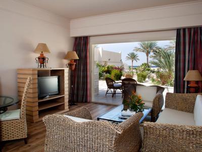 Przytulny salon hotelowy z meblami z wikliny i widokiem na taras i palmy.