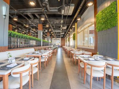 Moderní restaurace s dřevěnými židlemi a stoly v jasné, prostorné místnosti.