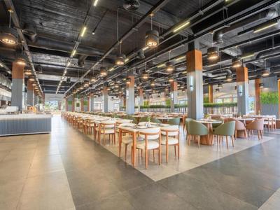 Moderní hotelová restaurace s dlouhou jídelnou a přirozeným osvětlením.