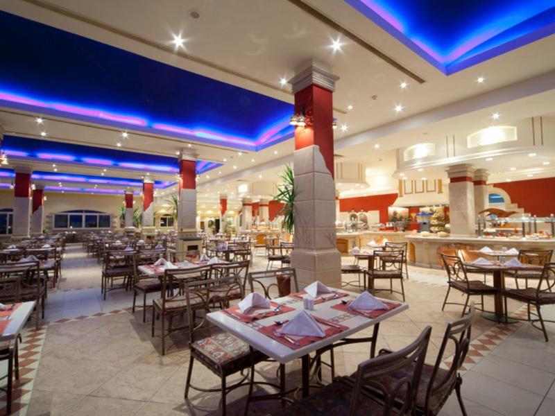 Moderní hotelová restaurace s prostřenými stoly a modrým stropním osvětlením.