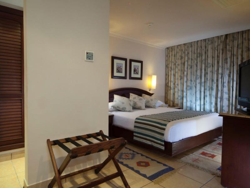 Hotelový pokoj s velkou postelí, lampičkami, závěsy a televizí na komodě