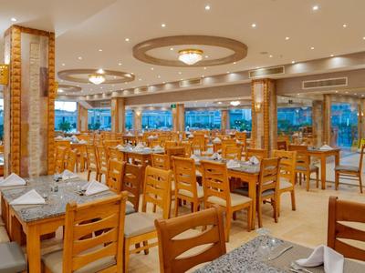 Large dining room with wooden furniture, many chairs, and set tables in a bright setting.