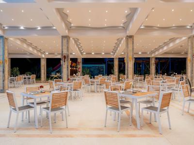 Large open dining area with modern chairs and tables under a bright, designed roof.