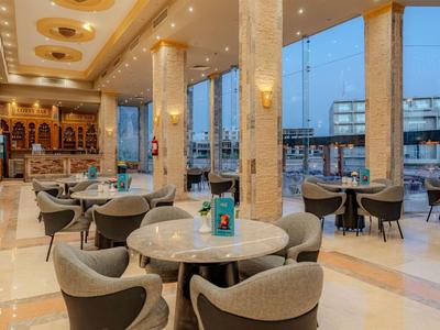 Elegant hotel dining room with marble, round tables, and panoramic windows showing city views.