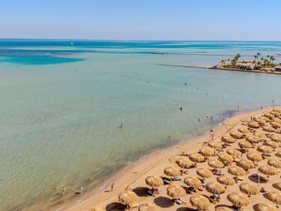 Beach with rows of sun umbrellas and calm blue sea in the background.