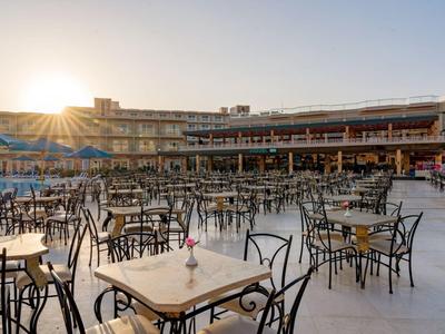 Large hotel terrace with many tables and chairs at sunset.