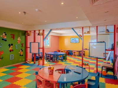 Colorful children's playroom with small tables, chairs, and toys in a hotel.