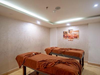 Calm massage room with two beds in warm brown and beige tones, perfect for relaxation.