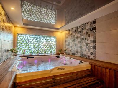 Hot tub with colorful lighting in a modern spa room with wood paneling and decorative tiles.