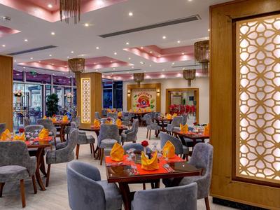 Modern hotel dining area with gray chairs, orange decorations, and decorative wall panel.