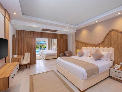 Modern hotel room with double bed, seating area, and access to an adjoining room.