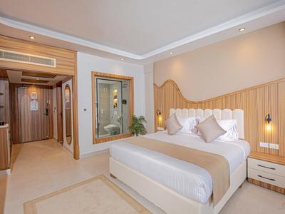 Modern hotel room with large bed, wood accents, and soft beige and brown tones.