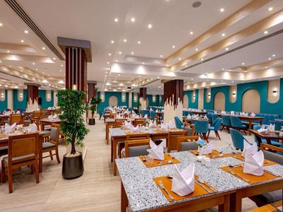 Spacious dining room with set tables, modern lighting, and decorative plants.
