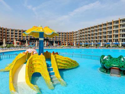Hotel pool with colorful water slides and a multi-story building in the background.