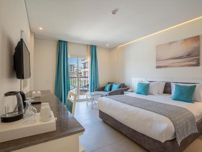 Moderner Hotelraum mit Doppelbett, Flachbildfernseher und Balkon mit Meerblick.