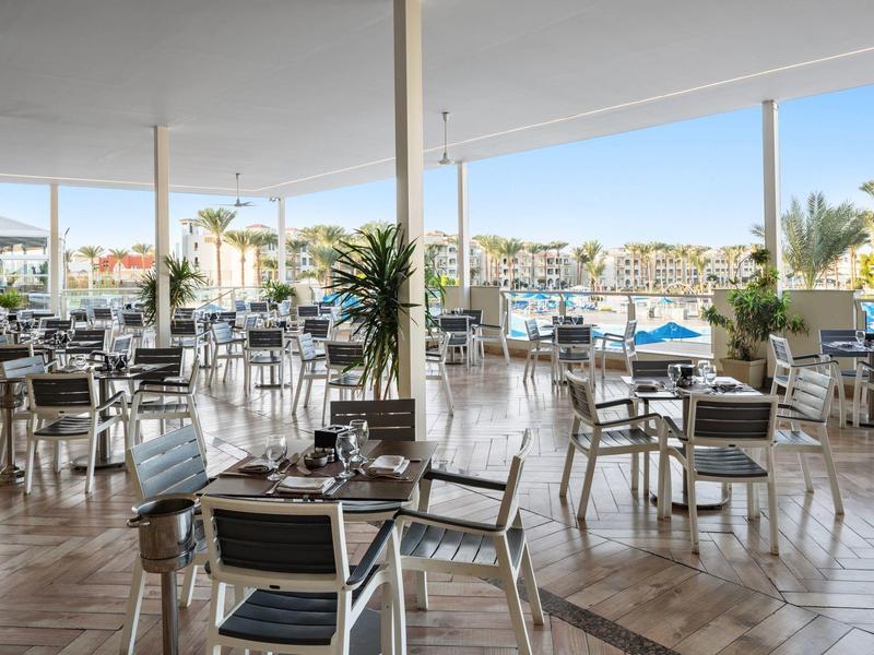 Otwarta restauracja ze stołami i krzesłami z widokiem na port i łodzie.