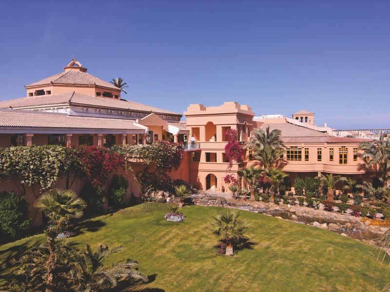 Hotel di lusso con giardini verdi sotto un cielo limpido.