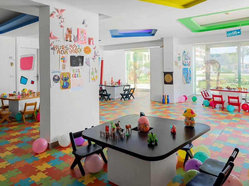 Sala giochi colorata per bambini con tavoli, sedie e giocattoli.