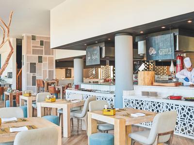 Jasna restauracja z drewnianymi i materiałowymi meblami, nowoczesną dekoracją i ladą.