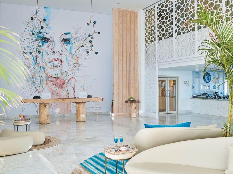 Moderna zona de vestíbulo de hotel con arte abstracto, plantas y asientos cómodos.