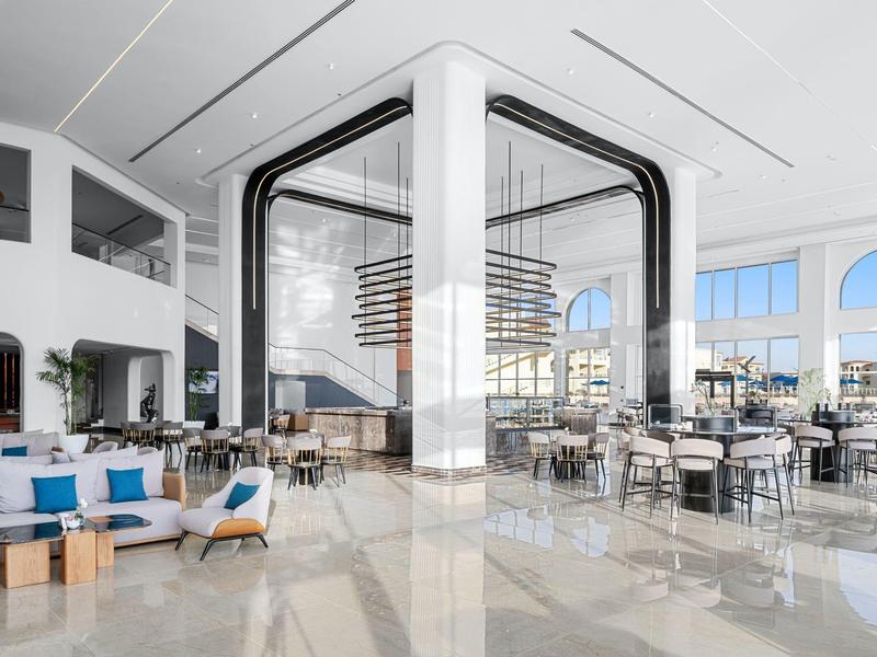 Ristorante di hotel moderno e luminoso con aree salotto e grandi finestre con vista mare.