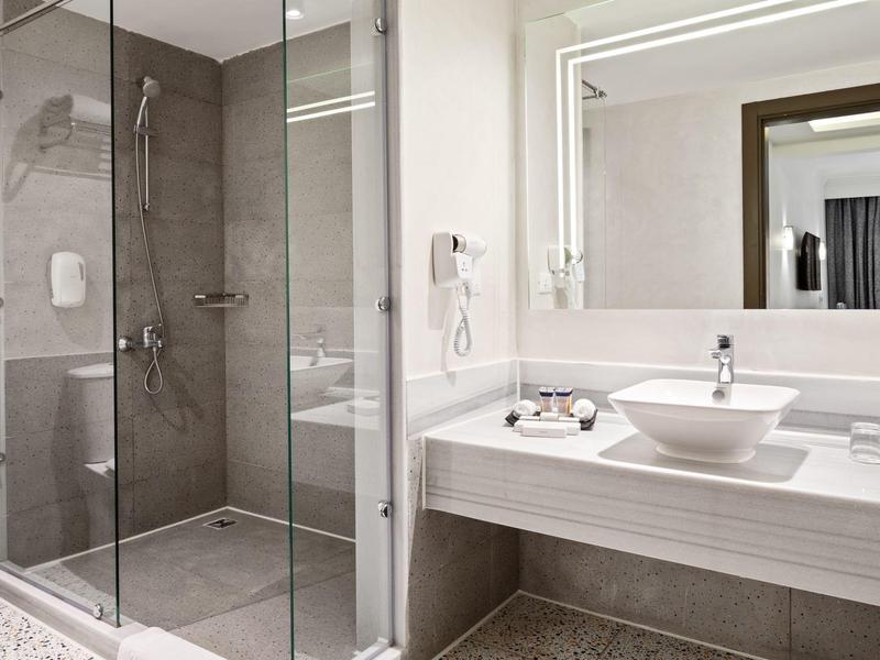 Salle de bain moderne avec douche vitrée et lavabo blanc sur plan de travail.