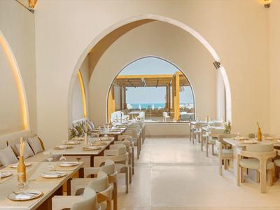 Bright and elegant hotel dining area with light-colored archways and neatly arranged tables.