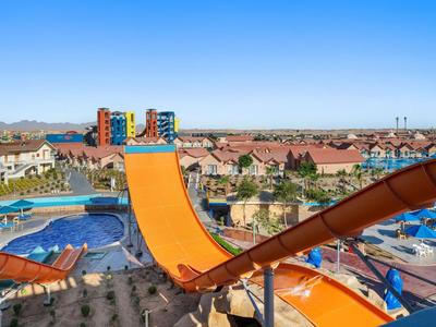 Parc aquatique avec grands toboggans colorés et plusieurs piscines par une journée ensoleillée.