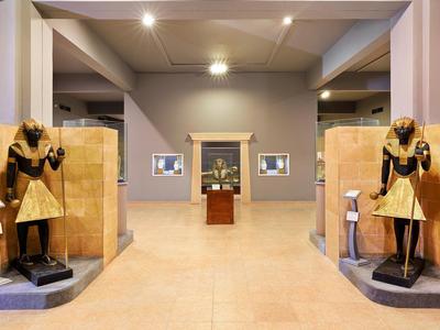 Entree van een museum met twee Egyptische standbeelden aan weerszijden van de deur.