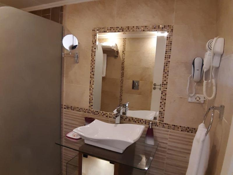 Bagno con lavabo, specchio incorniciato, asciugacapelli e asciugamano bianco.