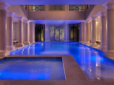 Wewnętrzny basen o niebieskim oświetleniu z kolumnami i jacuzzi w luksusowym hotelu.