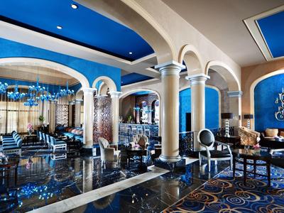 Luksusowy salon hotelowy z białymi kolumnami i królewskim niebieskim dekoracjami.