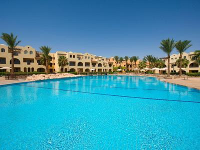 Grande piscine extérieure devant des bâtiments d'hôtel à plusieurs étages sous un ciel bleu clair