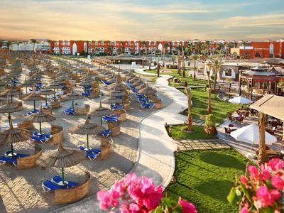 Vista panoramica di un'area spiaggia del resort con lettini sabbiosi, ombrelloni blu e prato curato