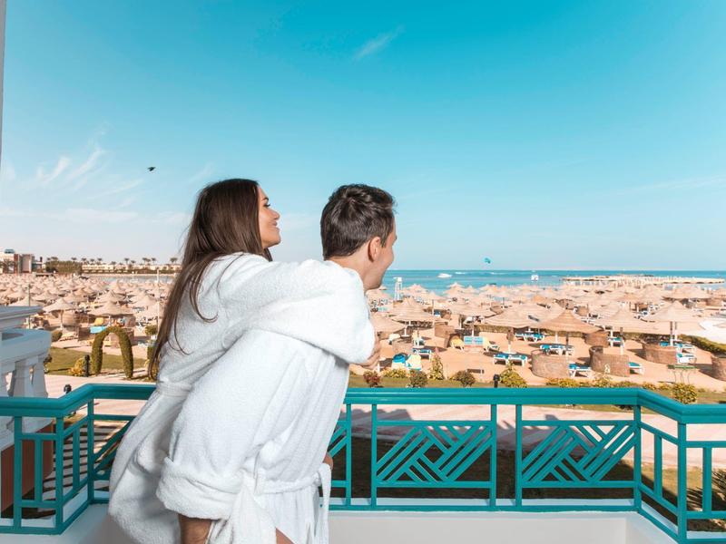Coppia che gode di una vista soleggiata dal balcone su una città con spiaggia.