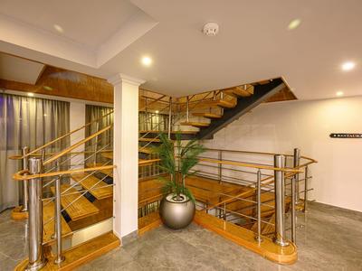 Moderne Holztreppe in einem hellen Hotelinnenraum mit Edelstahlgeländer und Pflanze.