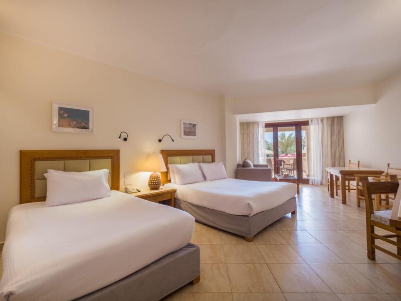 Przestronny pokój hotelowy z dwoma łóżkami, tarasem i jasnymi meblami drewnianymi.