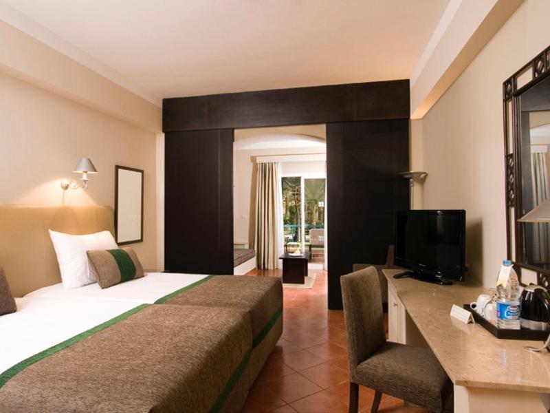 Modernes Hotelzimmer mit Doppelbett, Schreibtisch und Terrasse mit Gartenblick.