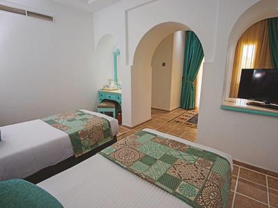 Hotelkamer met twee eenpersoonsbedden, boogvormige doorgang en een tv aan de muur.