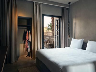 Schlafzimmer mit großem Bett, offener Kleiderschrank und Balkon mit Blick auf Nachbarschaft.