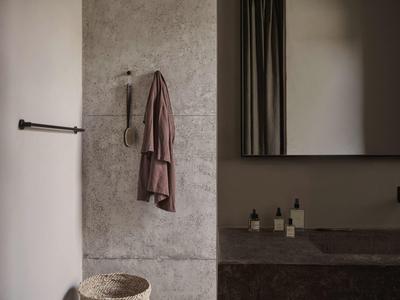 Modern bathroom with gray wall, towel hanging and mirror above stone sink.