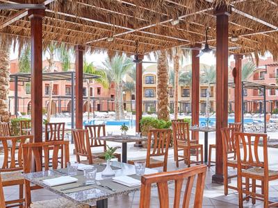 Taras restauracyjny z widokiem na basen i palmy w hotelu.