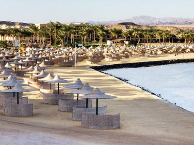Spiaggia sabbiosa vuota con ombrelloni e palme vicino al mare in un resort