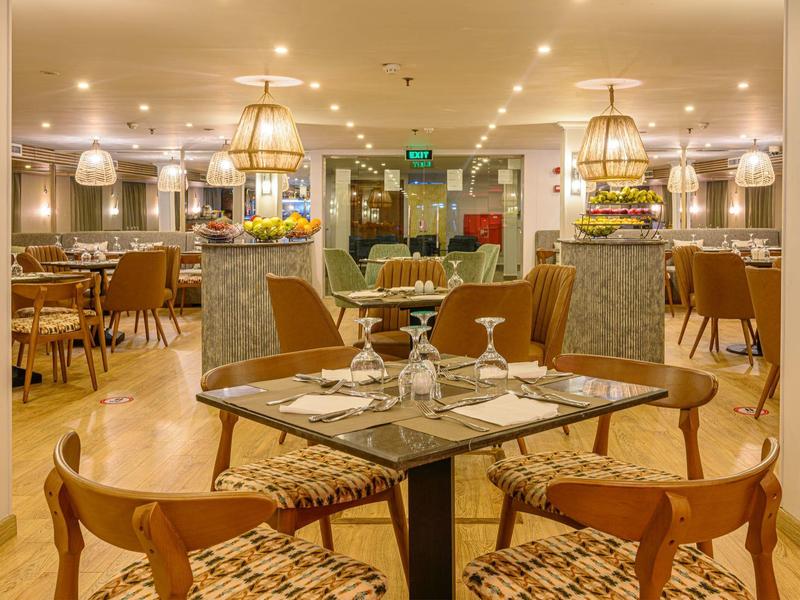 Moderne Restaurant mit Holzboden, gedeckten Tischen, bequemen Stühlen und warmem Licht.