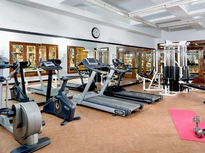 Fitnessraum mit Trainingsgeräten, Laufbändern und einer Matte mit Hanteln