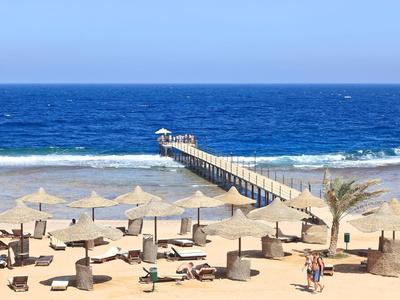 Strand mit Sonnenschirmen, Liegen und einem langen Steg ins blaue Meer